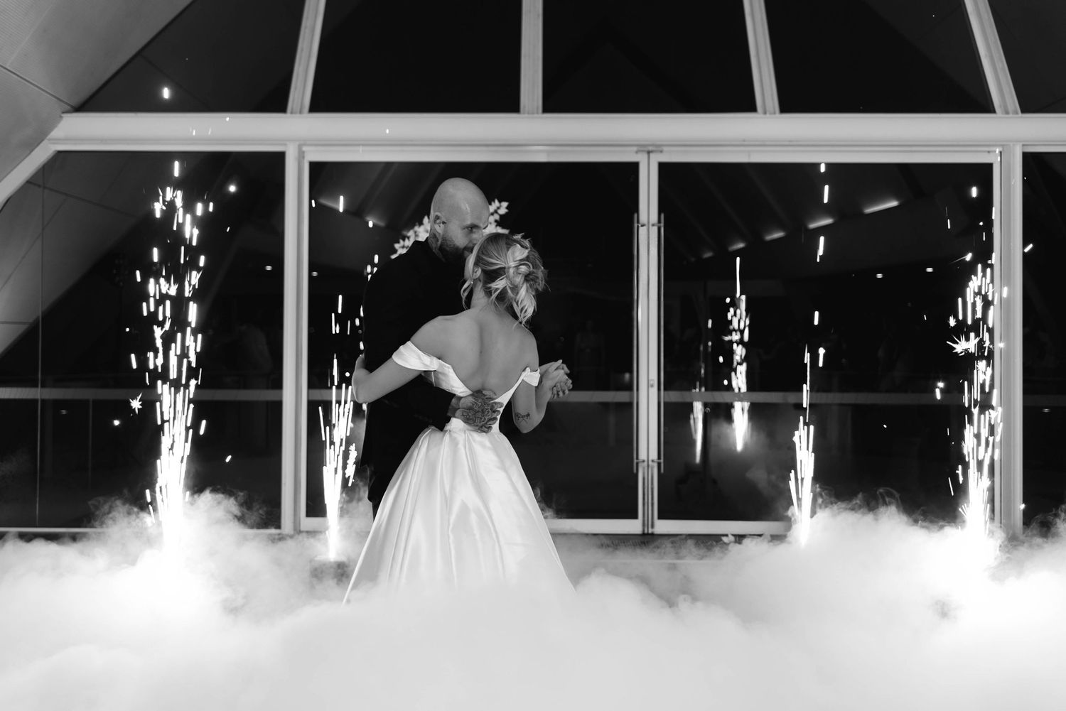 Sparklers create a magical light display behind a couple during their first dance at an elegant wedding reception.