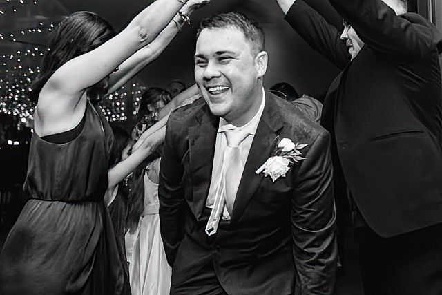 Wedding party members share laughter in formal black and white attire.