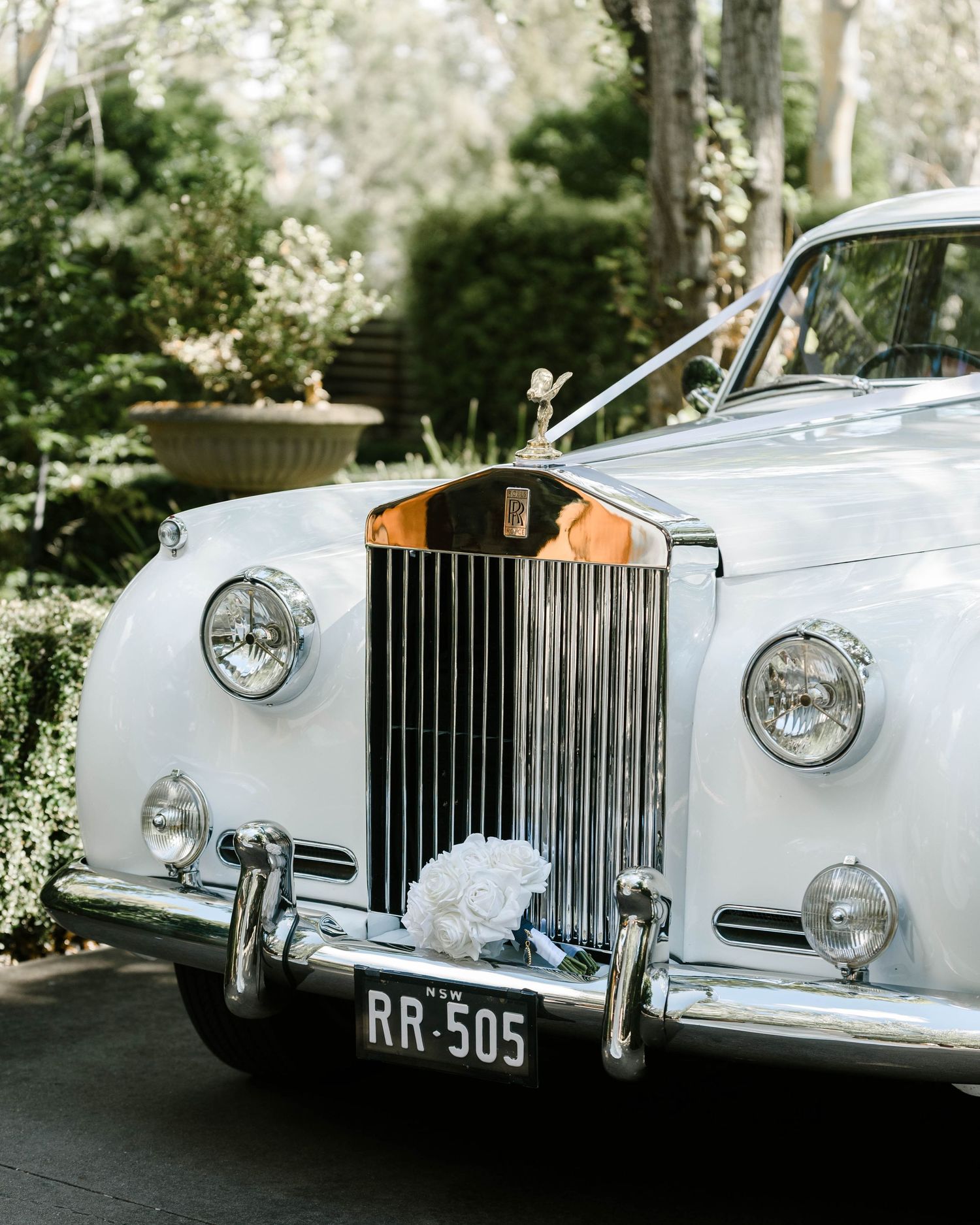 Classic white Rolls-Royce vintage wedding car with chrome grille and floral decoration.