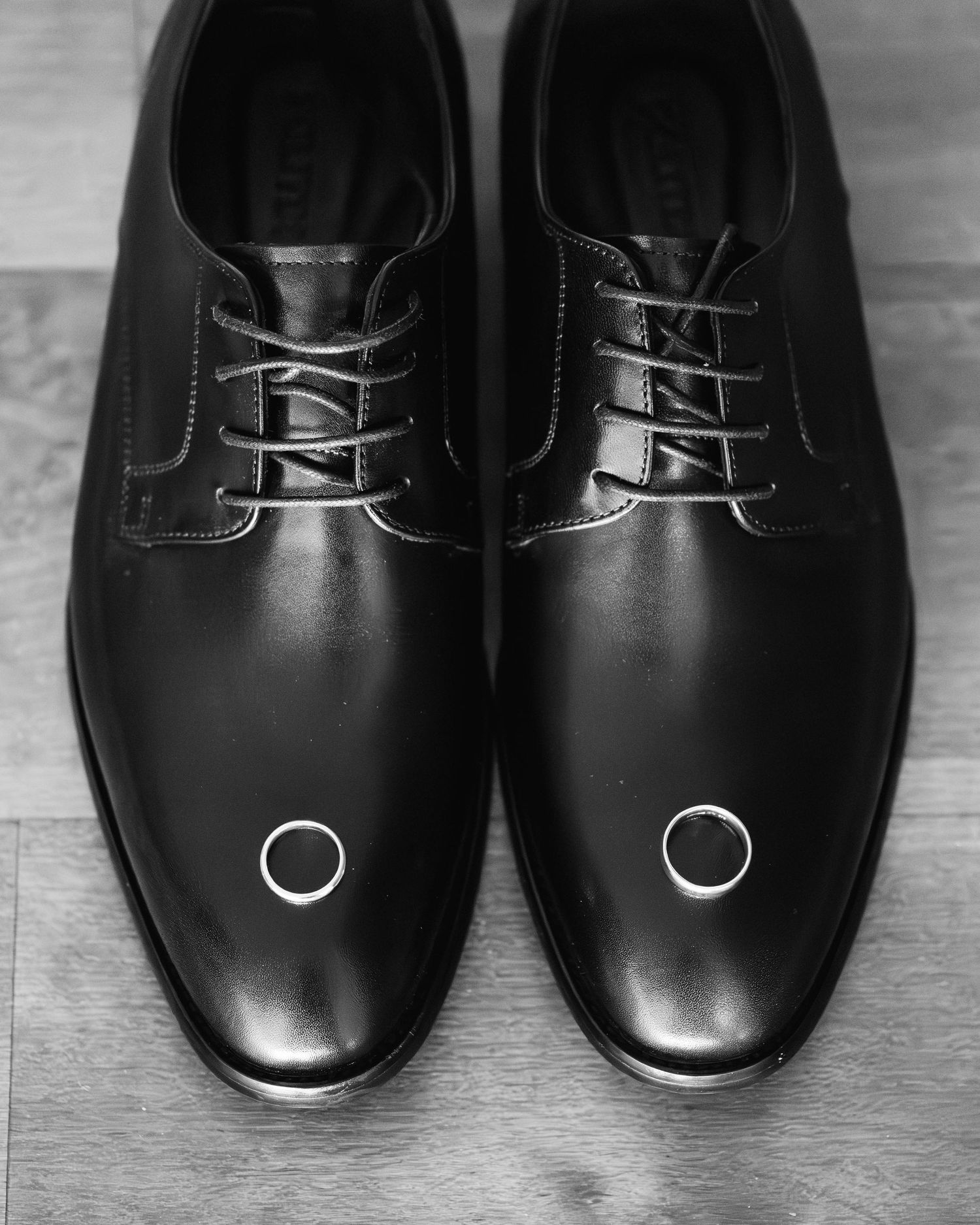 A sequence of black leather dress shoes arranged in a row showing different angles and perspectives on a light surface.