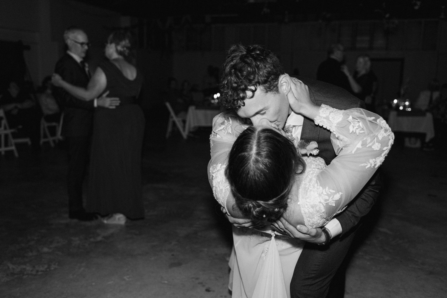 Black and white photo of bride and groom sharing first dance embrace at wedding reception.