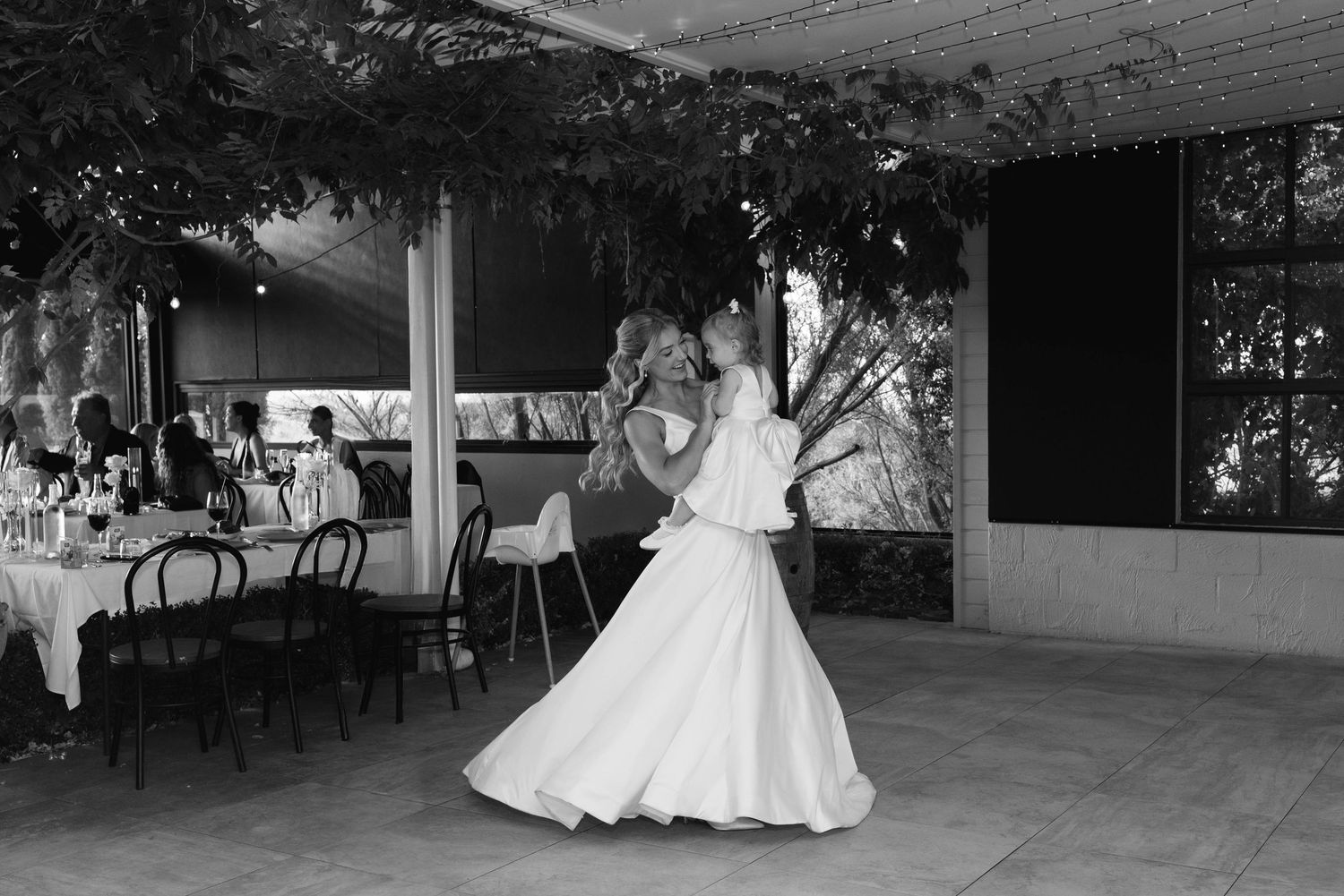 Bride dancing elegantly in a white gown during wedding reception in black and white photography.