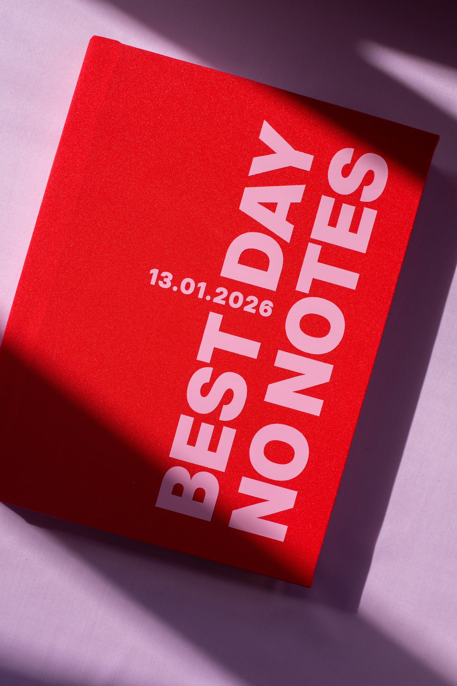 Red notebook with bold white text reading BEST DAY NO NOTES dated 13.01.2026, photographed on a light purple surface.