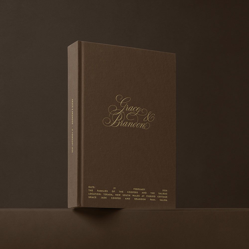 Elegant dark brown hardcover wedding photo book with gold foil names Grace and Brandon embossed on cover.