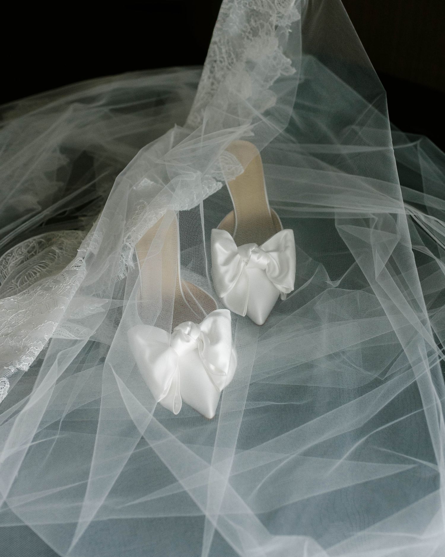 Flowing white tulle fabric creates ethereal layers and movement in an artistic arrangement against a dark background.