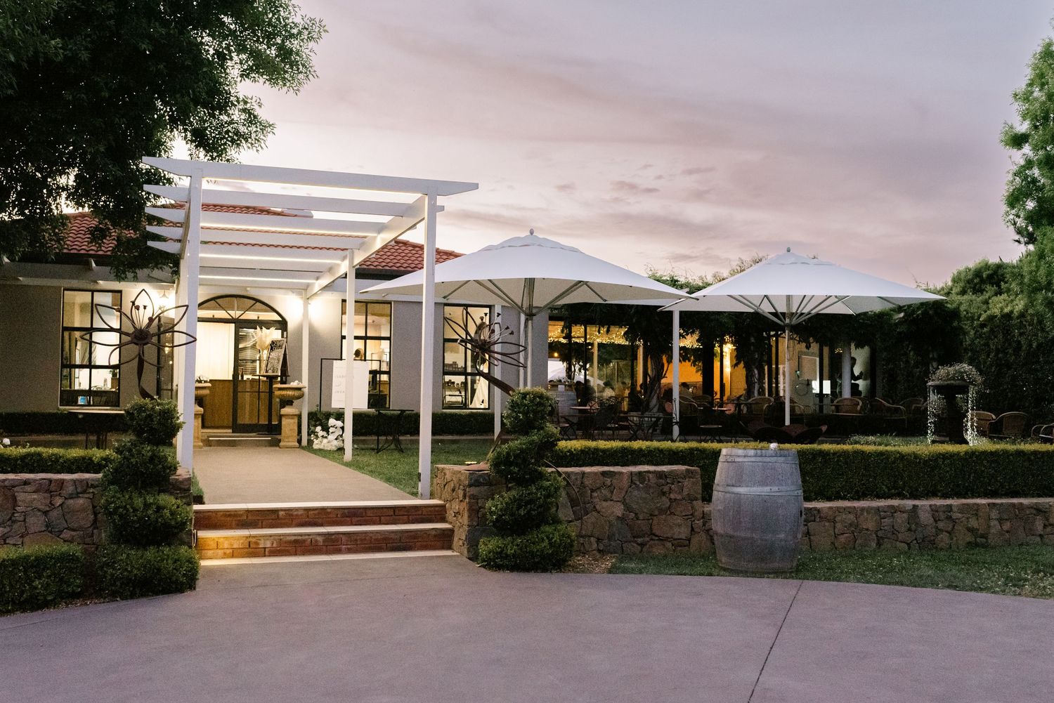 Modern outdoor wedding venue with white tent and stone walls at sunset.