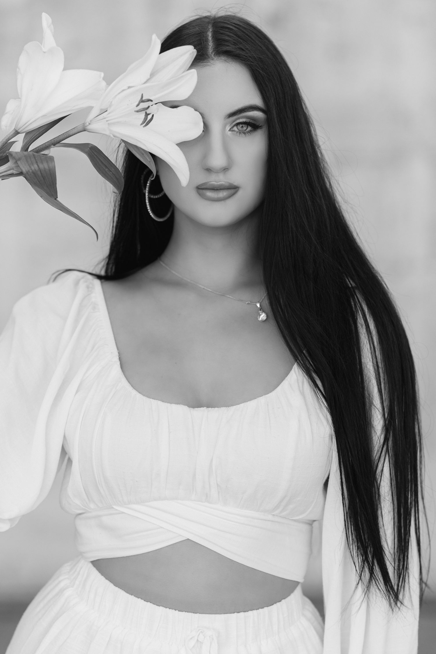 Ethereal portrait series with white lilies and flowing white fabric against light background.