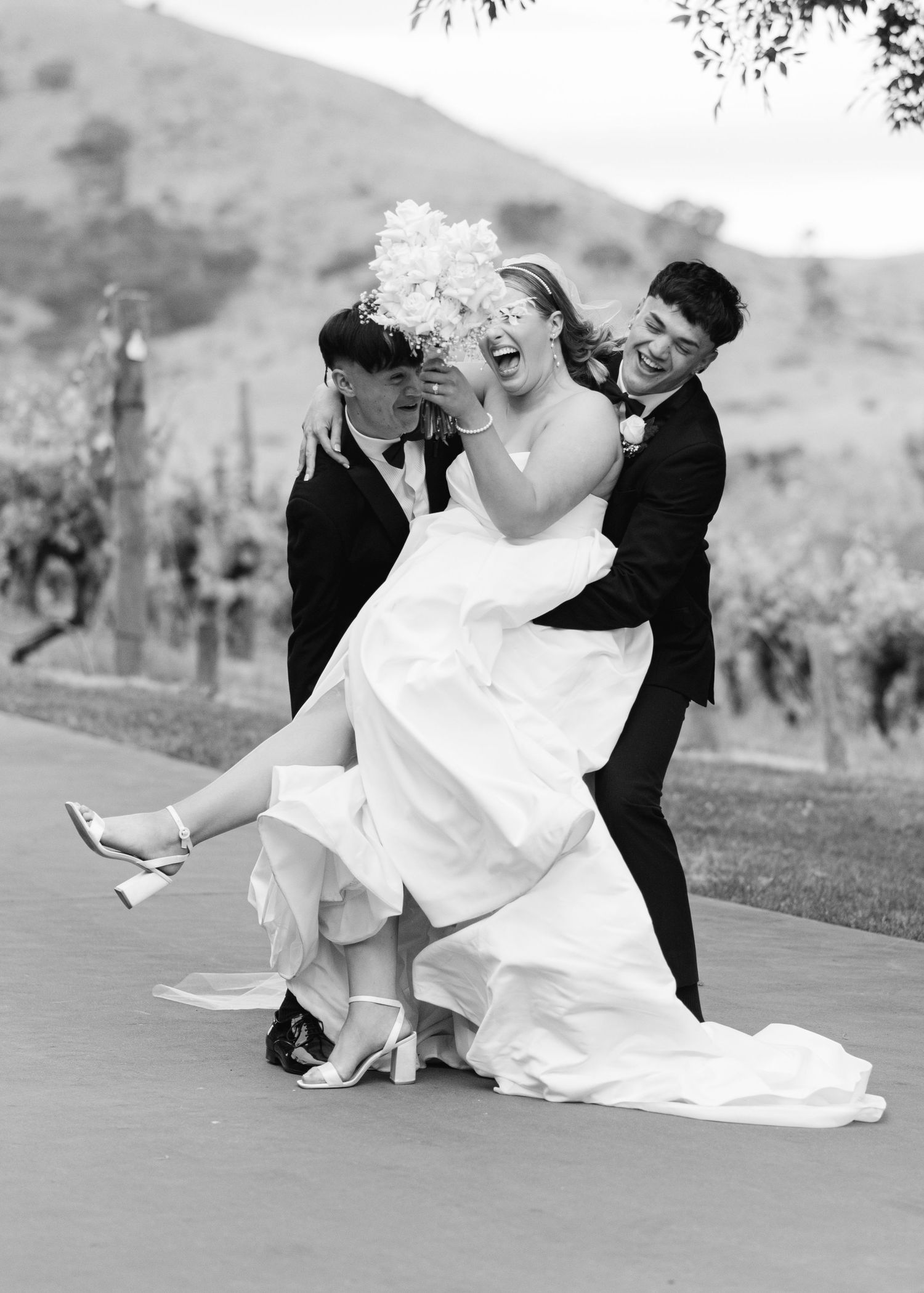 A black and white collage of wedding photos showing a couple playfully posing in formal attire on grassy grounds.