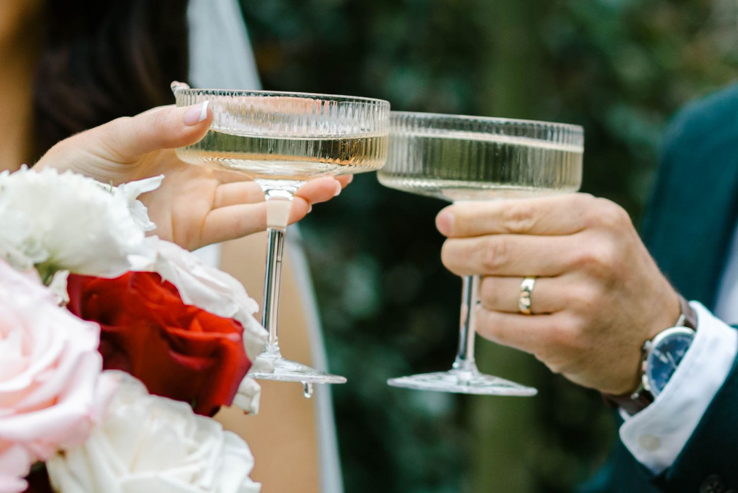 Two hands clink champagne glasses together in celebration at a formal event.