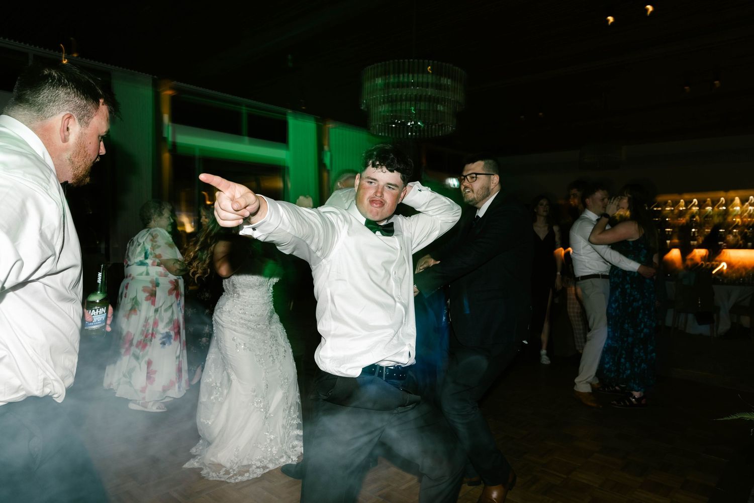 Newlyweds share their first dance surrounded by guests at an evening wedding reception.