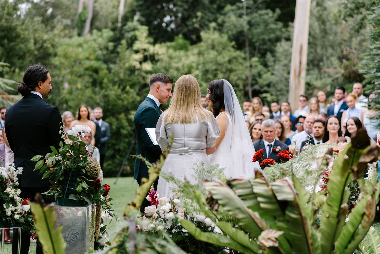 A romantic outdoor wedding ceremony setup with wooden chairs and floral arrangements in a garden setting.