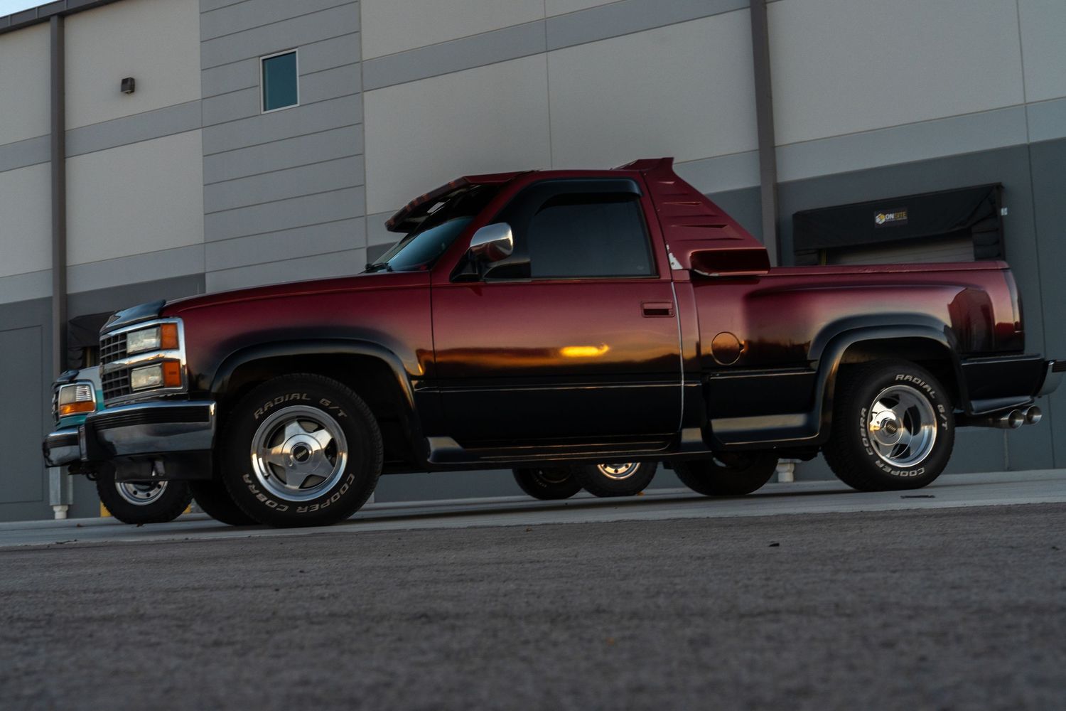 Row of red pickup trucks lined up in a parking lot at dusk.
