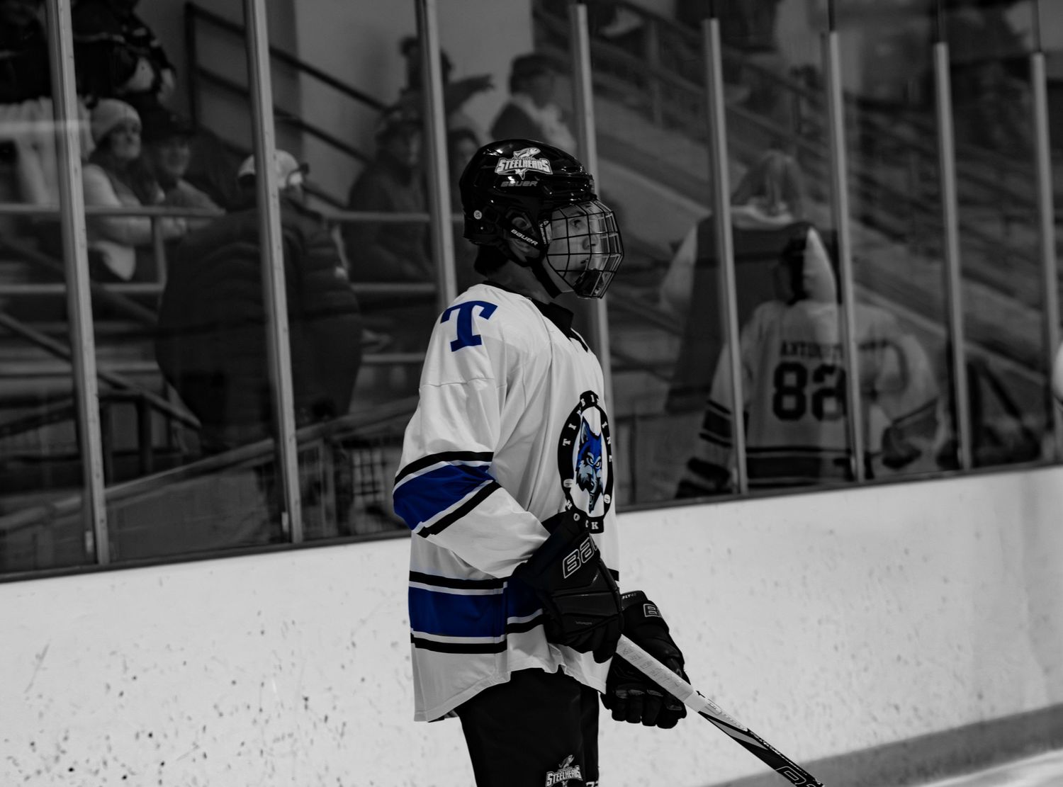 Hockey player in white and blue uniform standing on ice during a game.