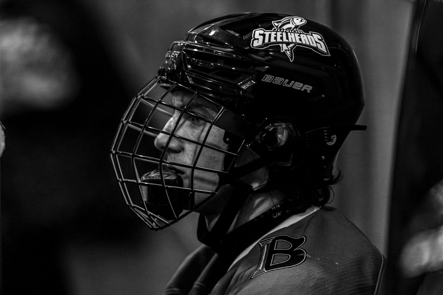 Hockey players in black jerseys gather around their goalie during a game break on the ice rink.