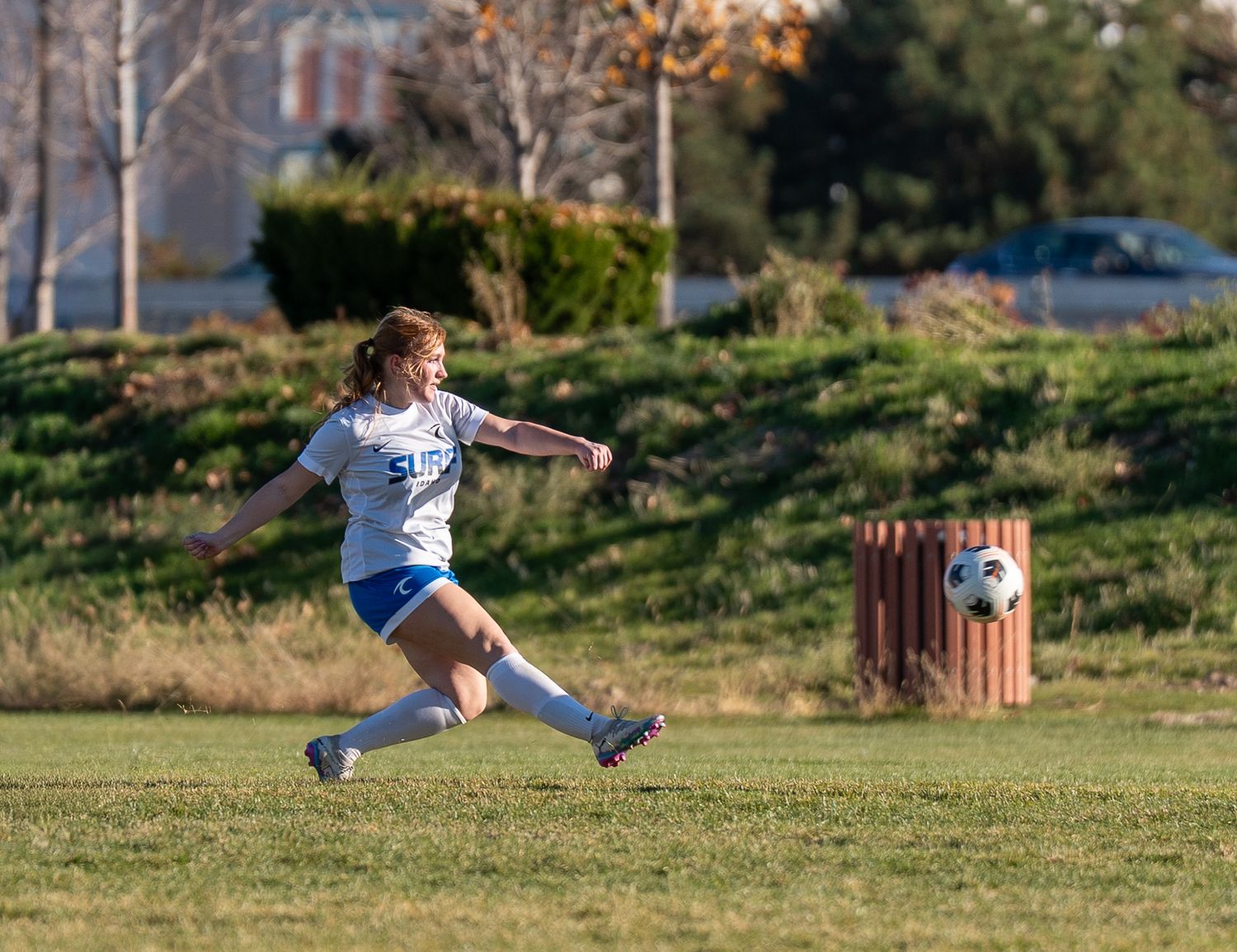 Soccer player in motion preparing to kick ball on autumn field.