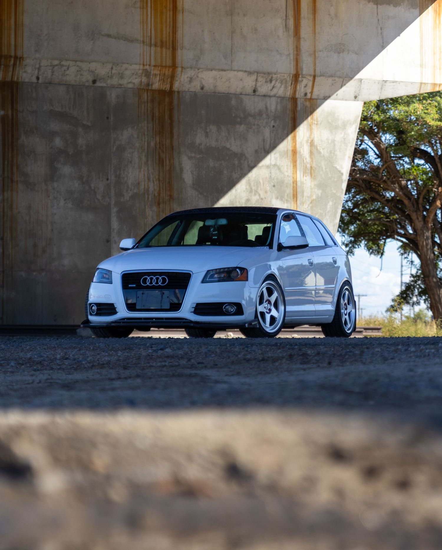 White Audi sports cars parked under concrete overpass in dramatic lighting.