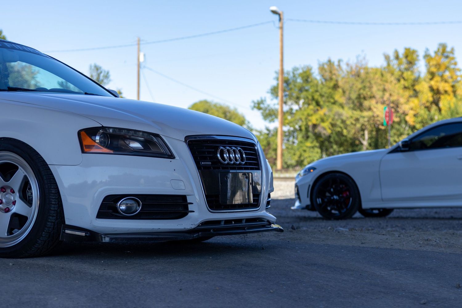 Line of luxury vehicles parked on asphalt with utility poles in background.