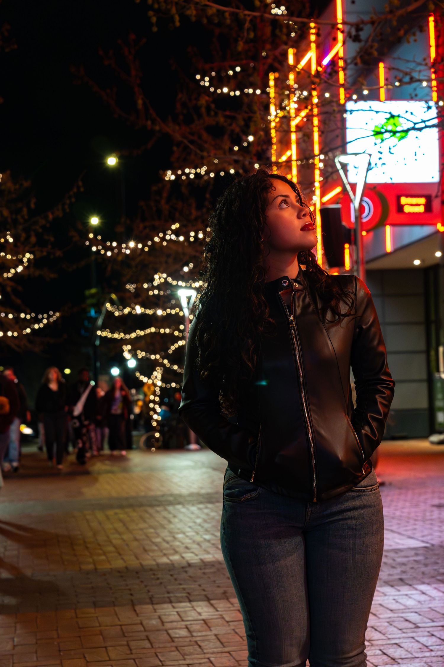 Nighttime street scene with twinkling lights and brick pathways.