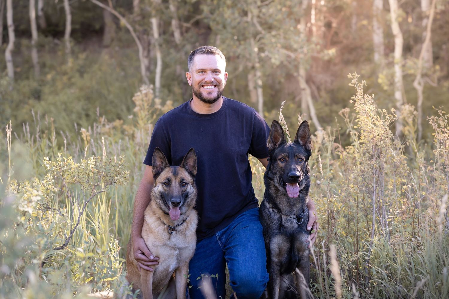 Family and their German Shepherd dogs posing together in natural landscape.