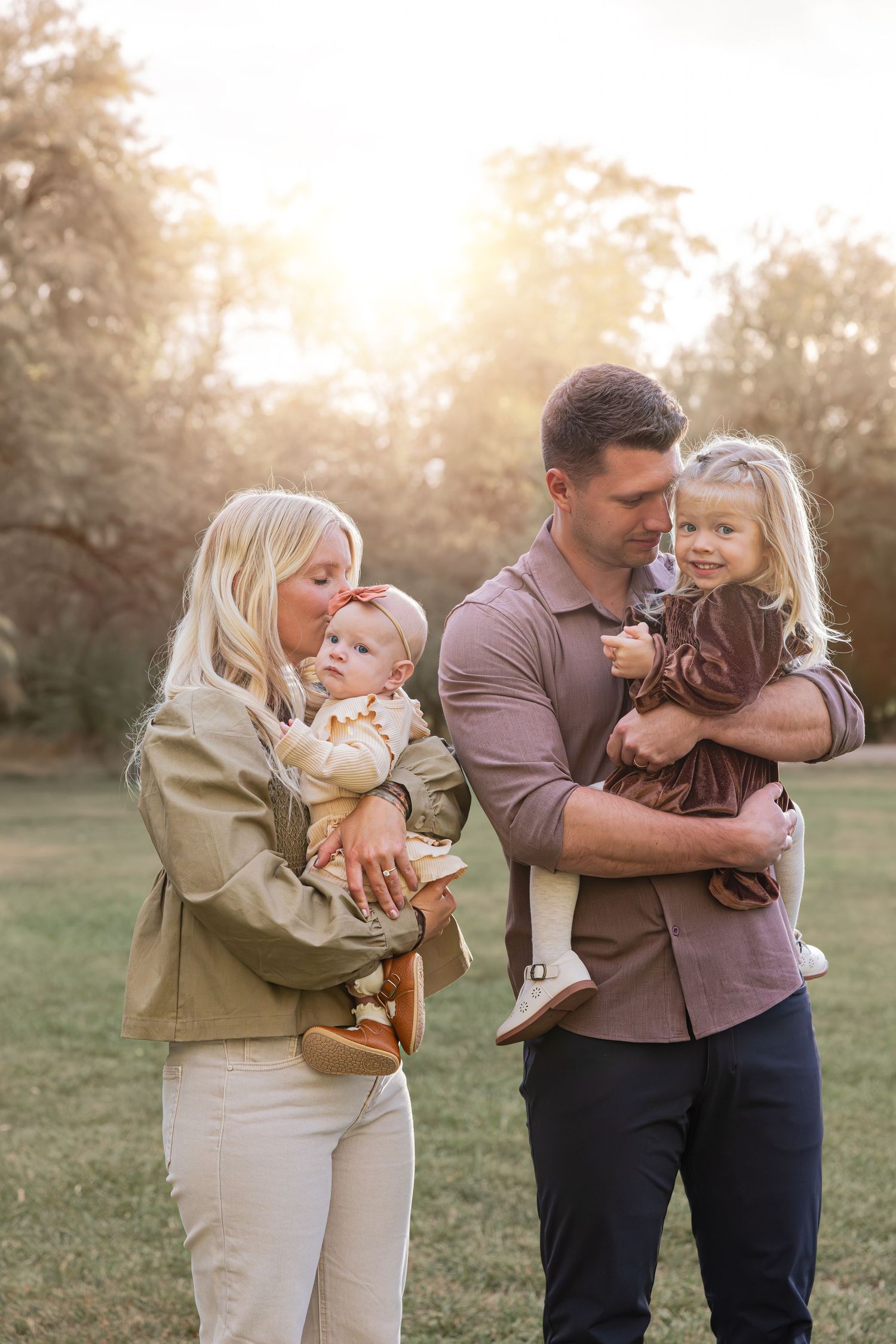 A loving family shares tender embraces in a sunlit field during golden hour.