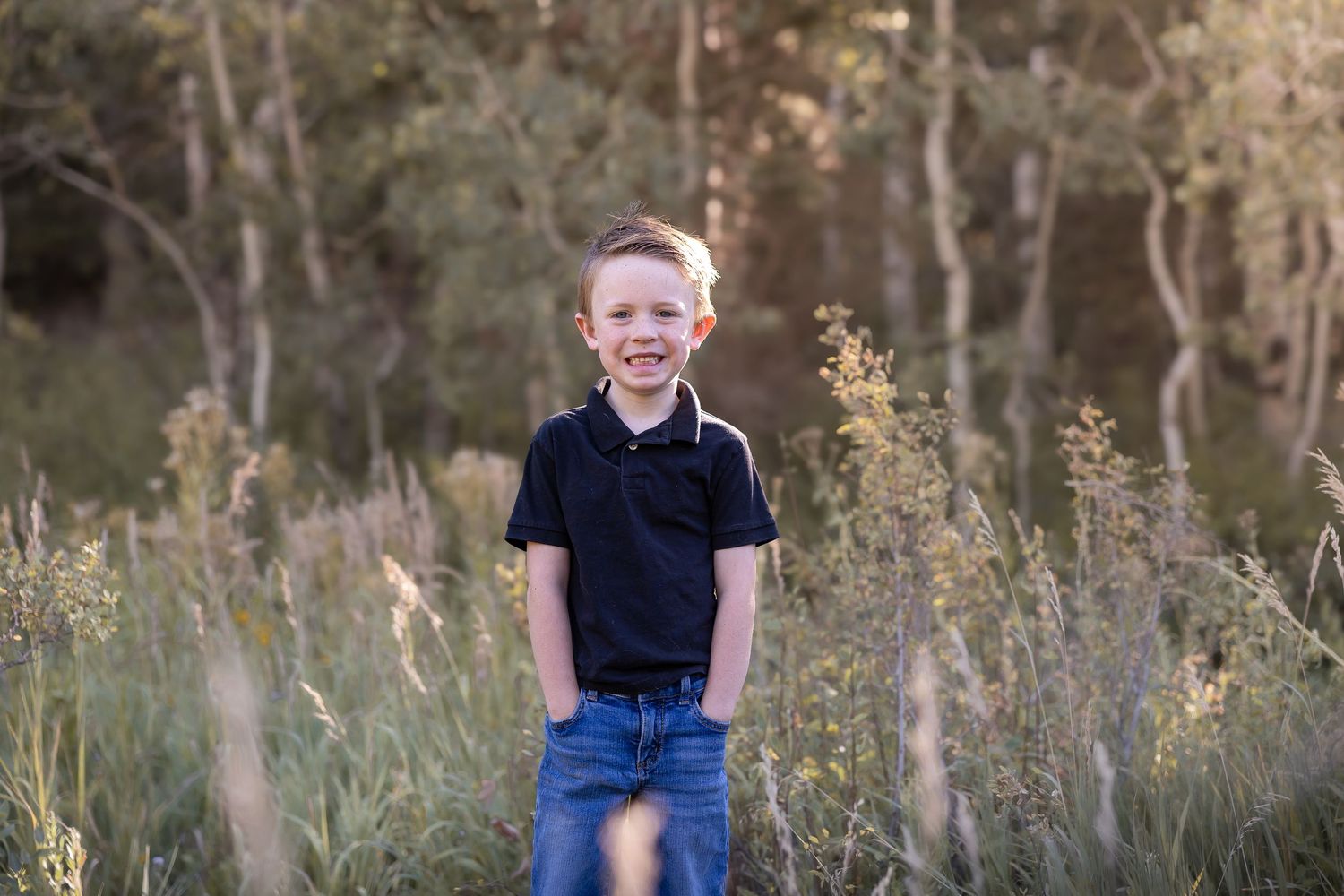 Children playing in a field of tall grass and wildflowers at sunset.