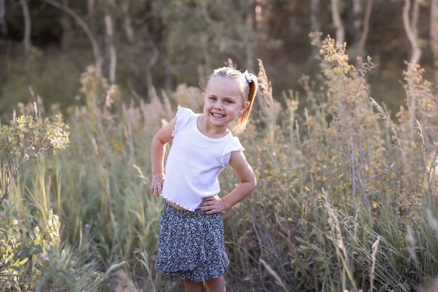 Candid outdoor family photos taken in a sunlit meadow with tall grasses.
