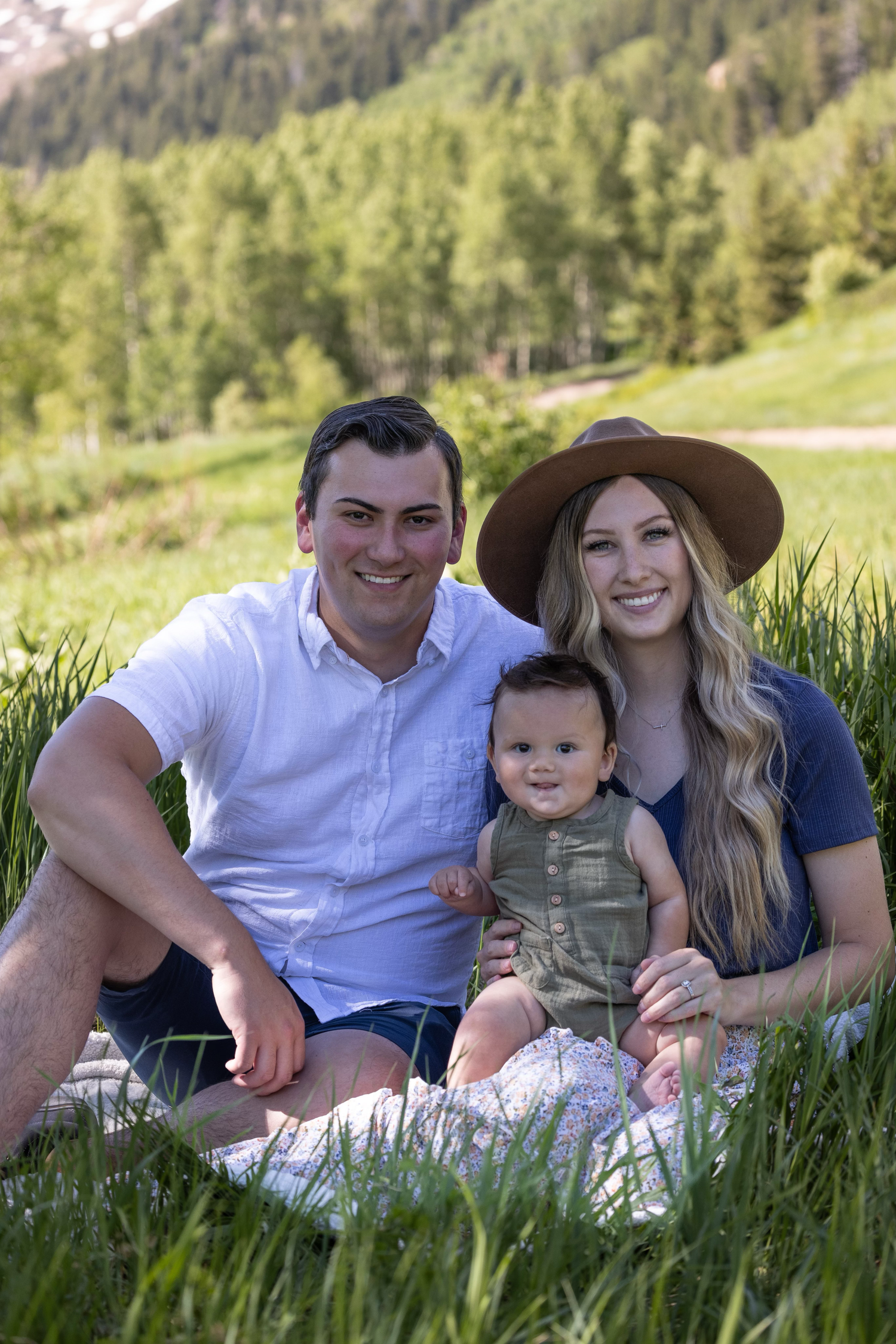 Family portrait taken in mountain meadow with forest backdrop.