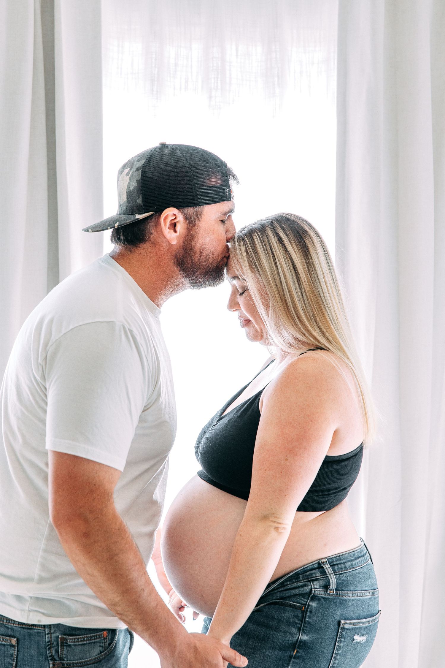 Intimate maternity photos captured against bright window light.