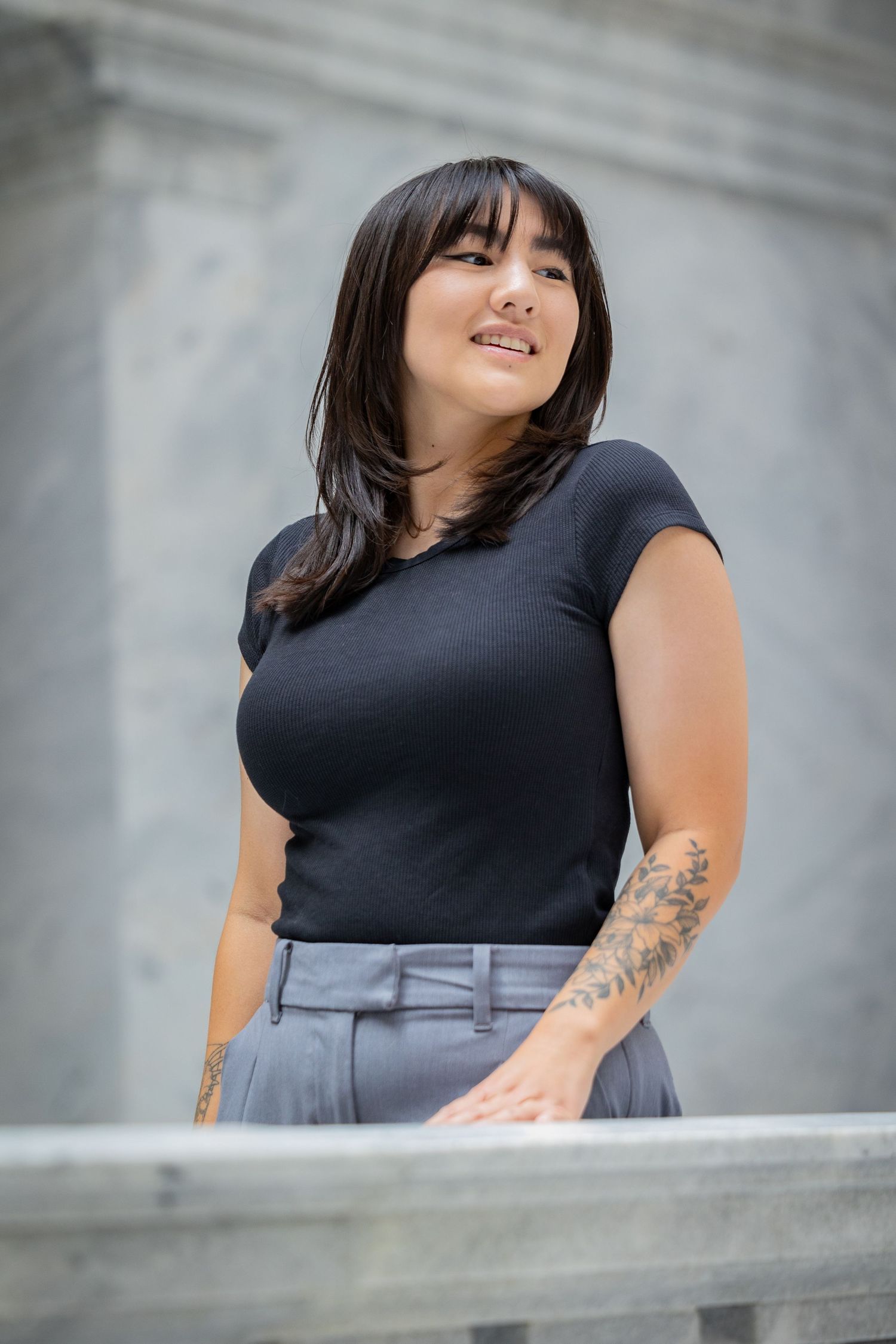 Fashion photoshoot showcasing dark top and gray pants against classical architecture.