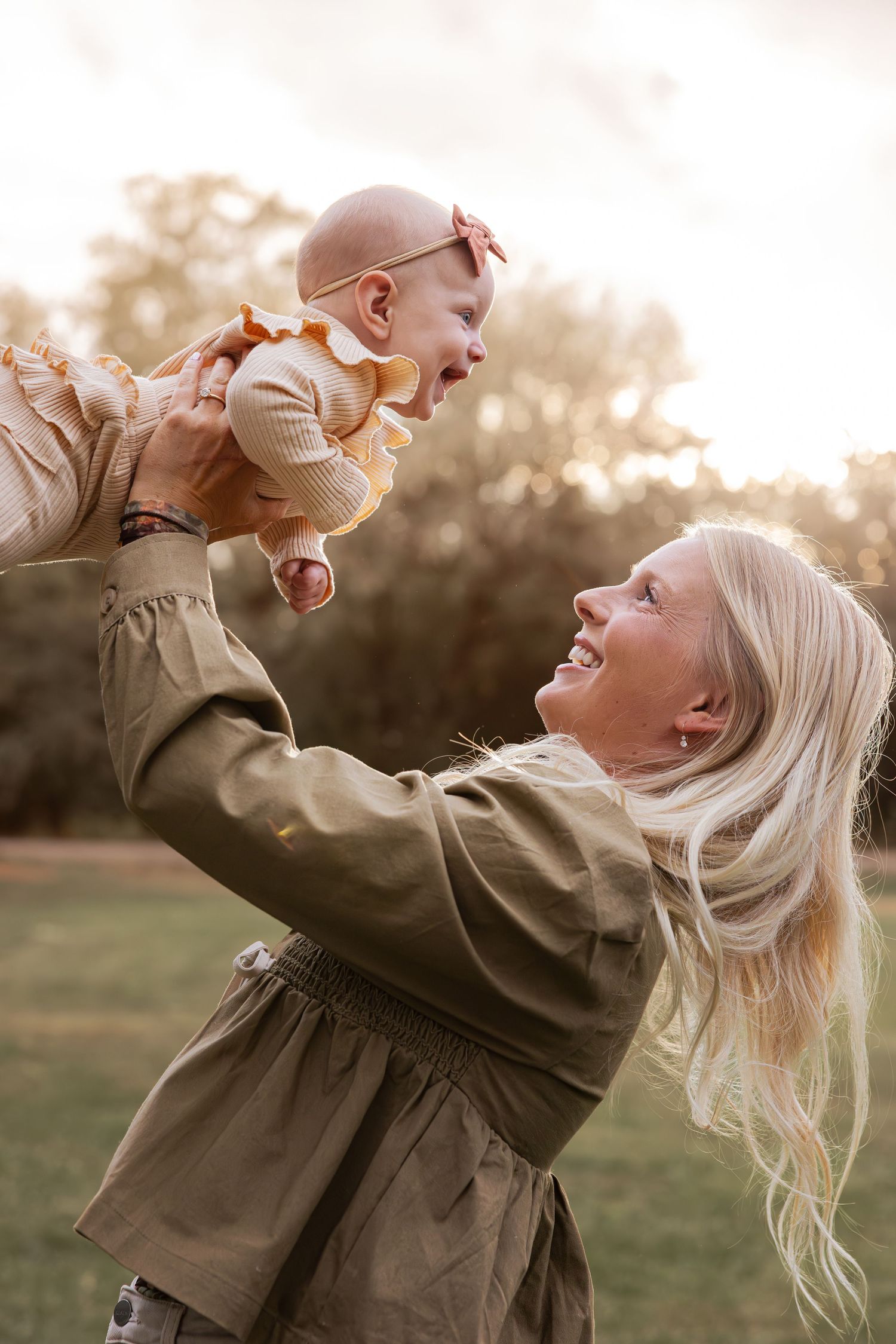 A joyful moment captured between parent and baby during golden hour outdoors.