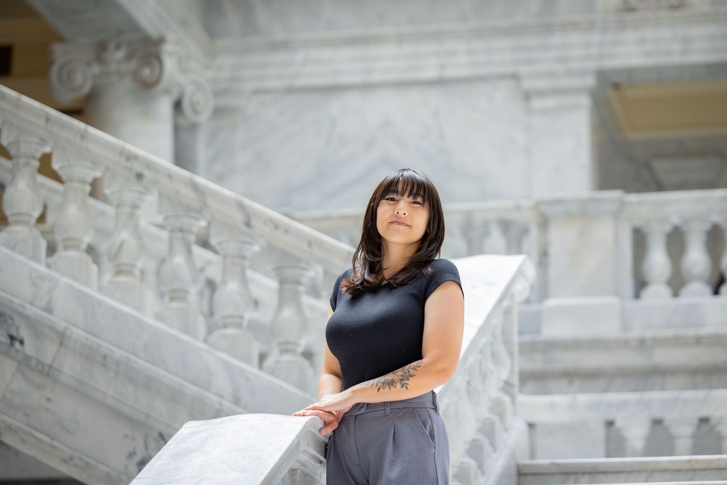 Portrait of person leaning on ornate marble railing in government building.