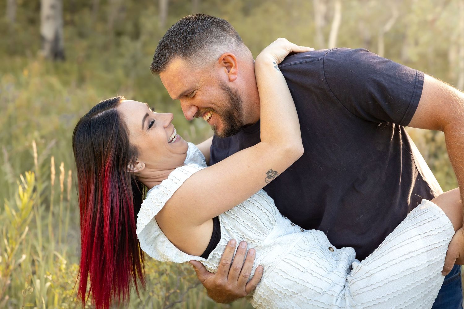 Couple dancing and dipping pose in meadow during golden hour.