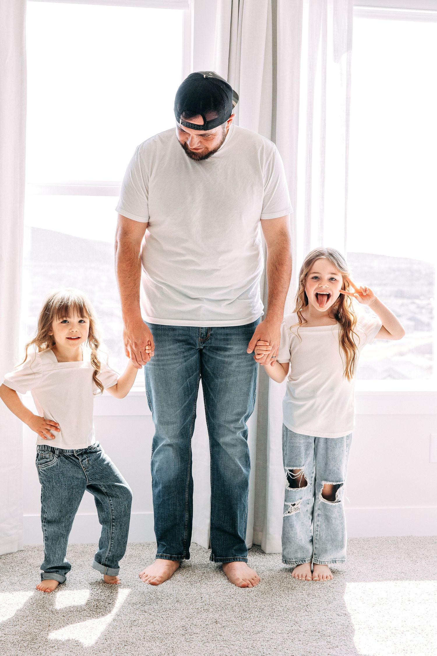 Family having fun and laughing together on carpeted floor by bright windows.