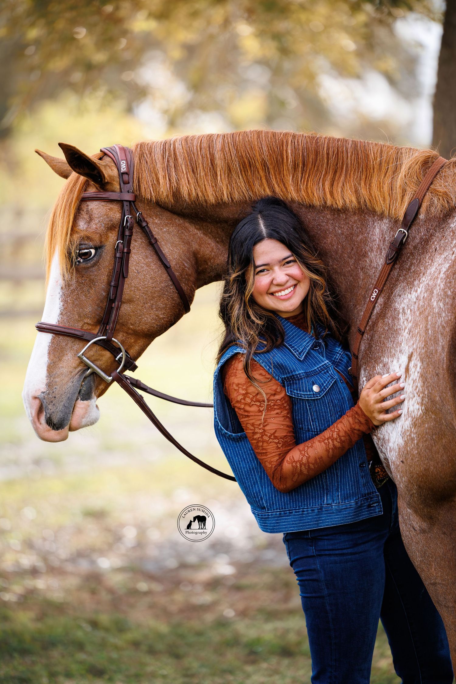 Brown horse being affectionately embraced by someone in denim overalls and brown jacket.
