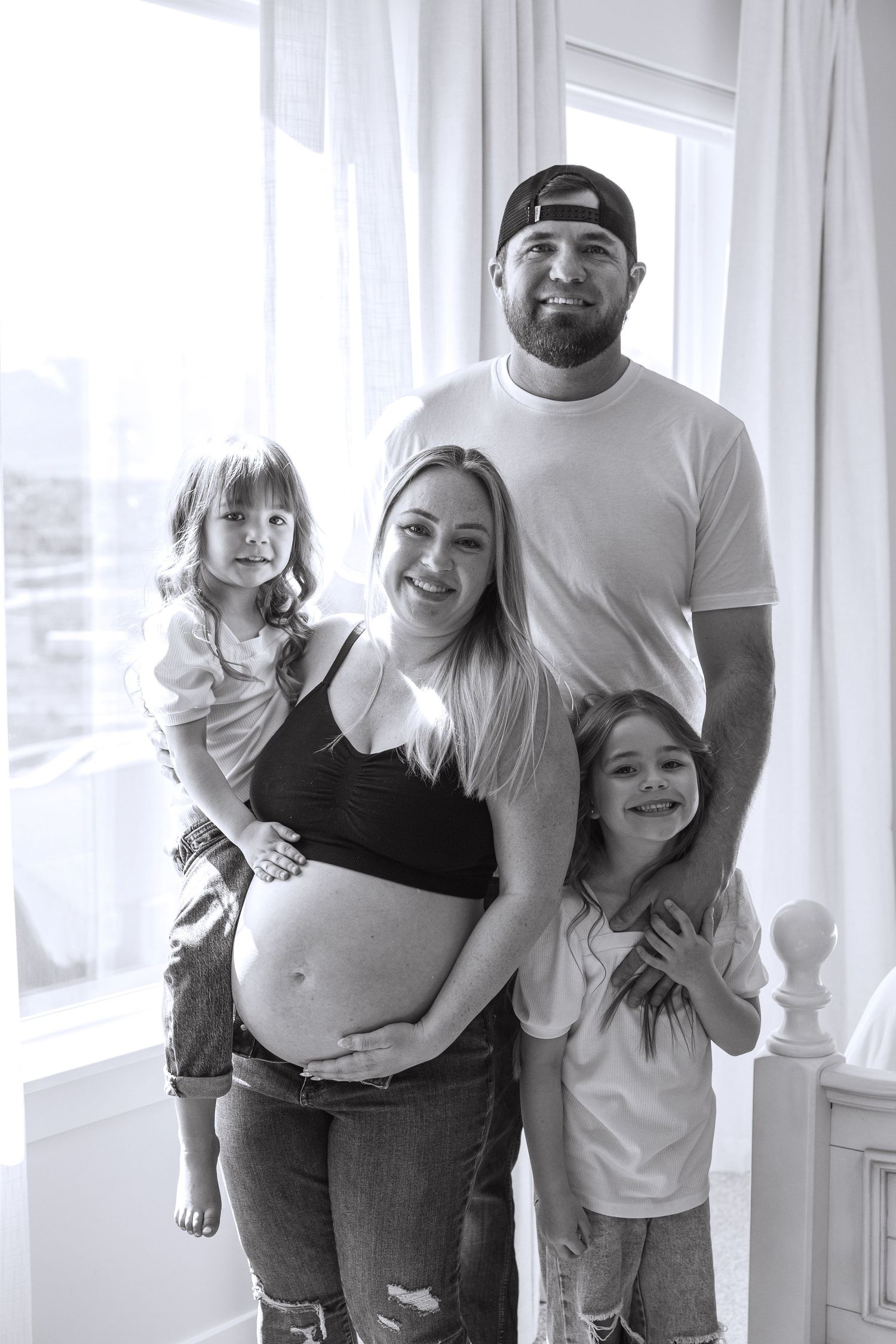 A family shares joyful moments together in a bright indoor setting with white curtains.