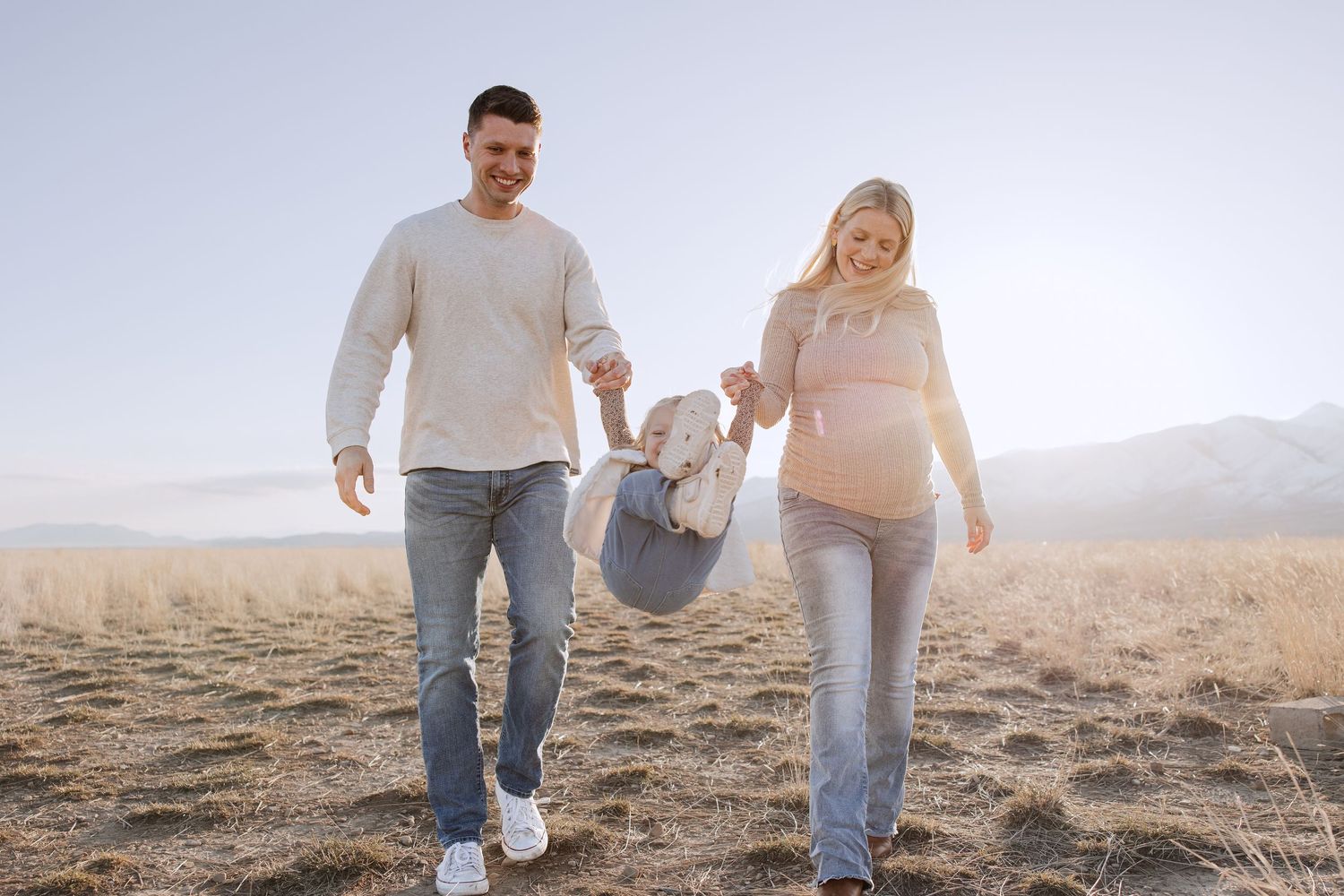 A family walks together through a golden field at sunset.