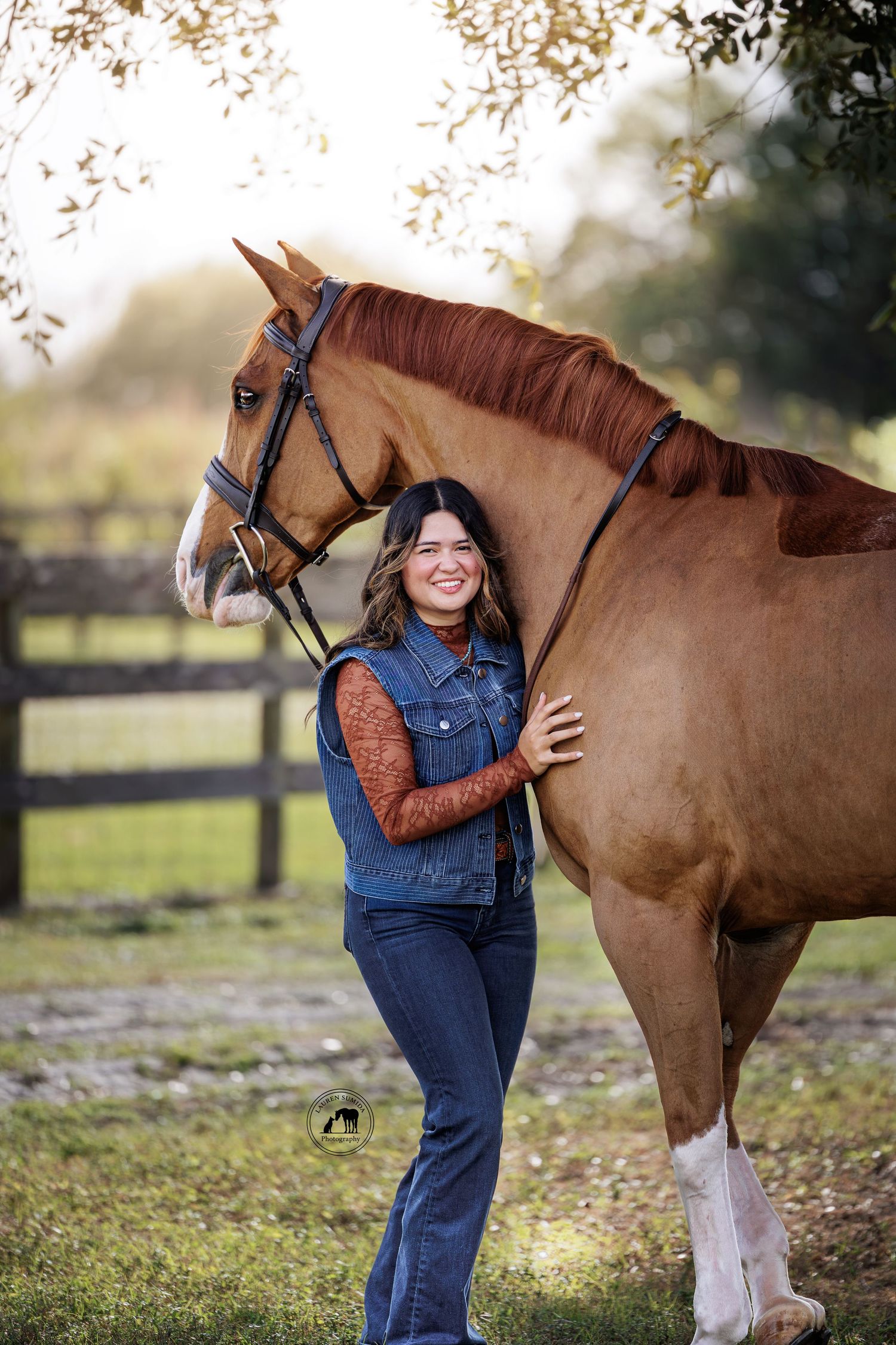 A person in denim overalls shares a tender moment with a chestnut horse in a pastoral setting.