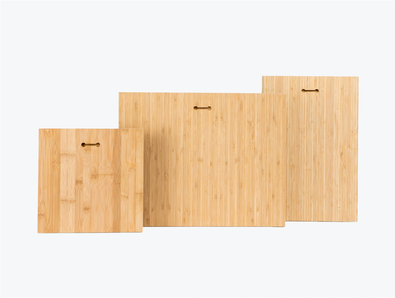 Three light wooden bamboo cutting boards of different sizes arranged in ascending order against white background.