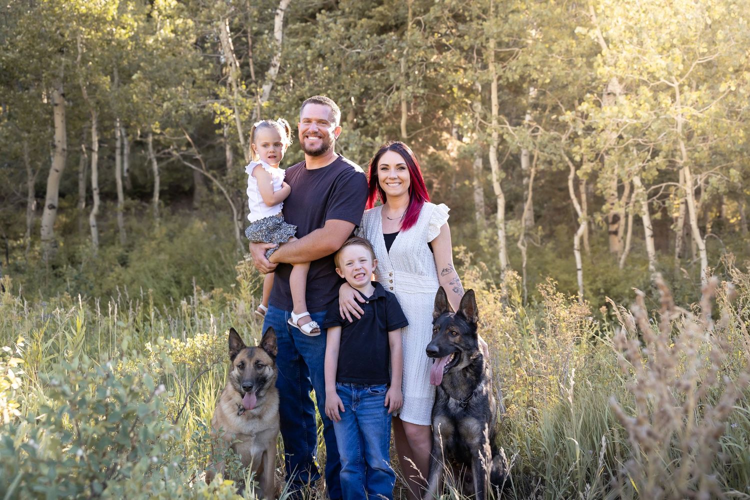 Family group photo with German Shepherd dogs in a scenic outdoor setting.