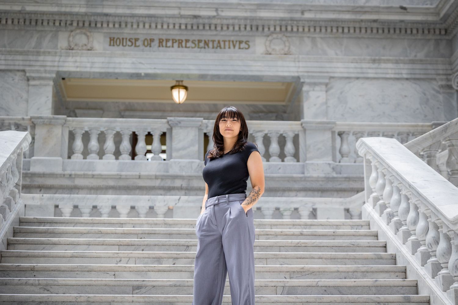 Person poses on marble staircase at House of Representatives building.