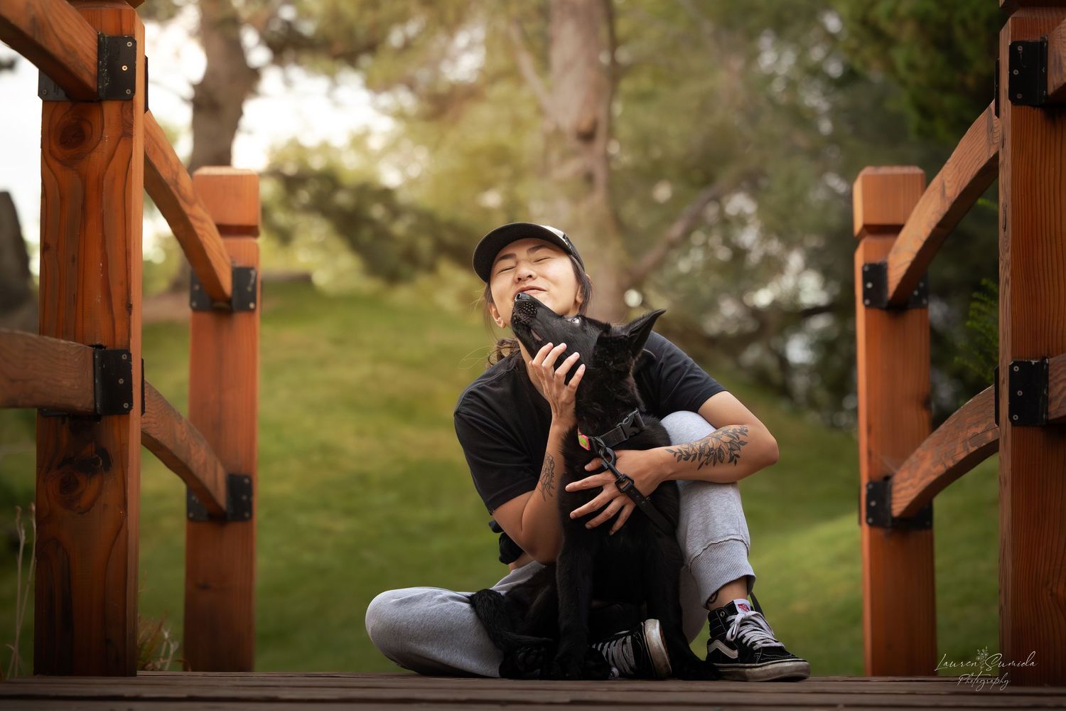 Photographer sitting on wooden deck with camera equipment in outdoor setting.