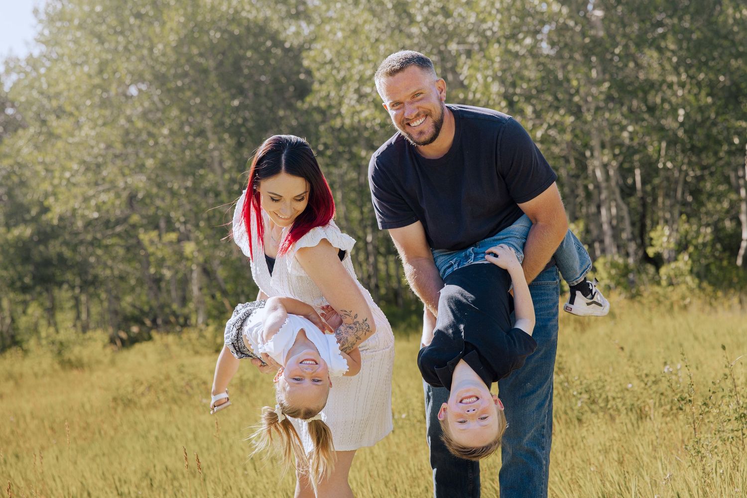 Family playing and having fun together in a sunny meadow with trees.