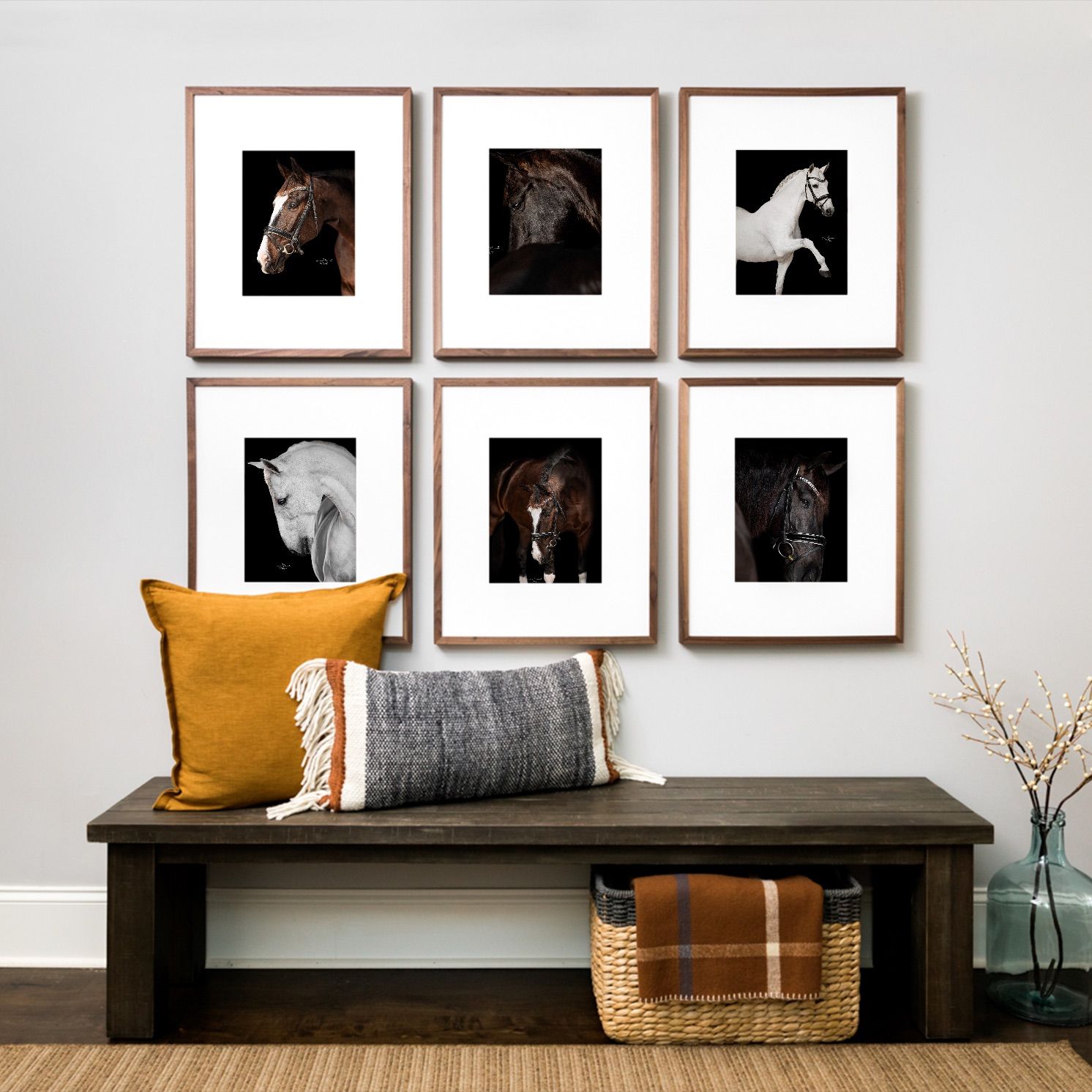 Six framed horse portrait prints on a wall above a wooden bench with orange pillow and wicker basket.