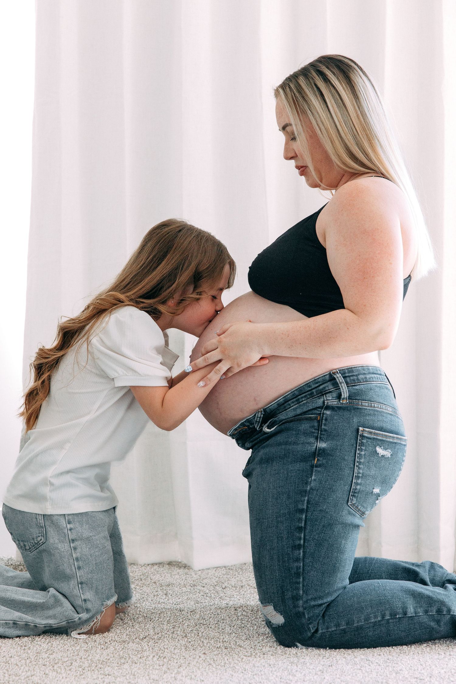 Maternity moment captured with child hugging mother's pregnant belly.
