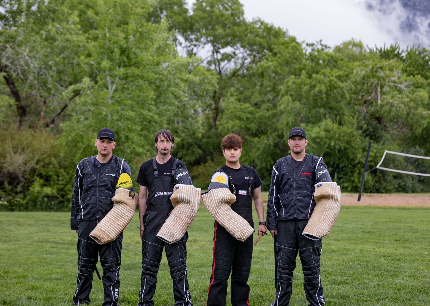 K9 training team members stand in formation holding protective training sleeves outdoors.