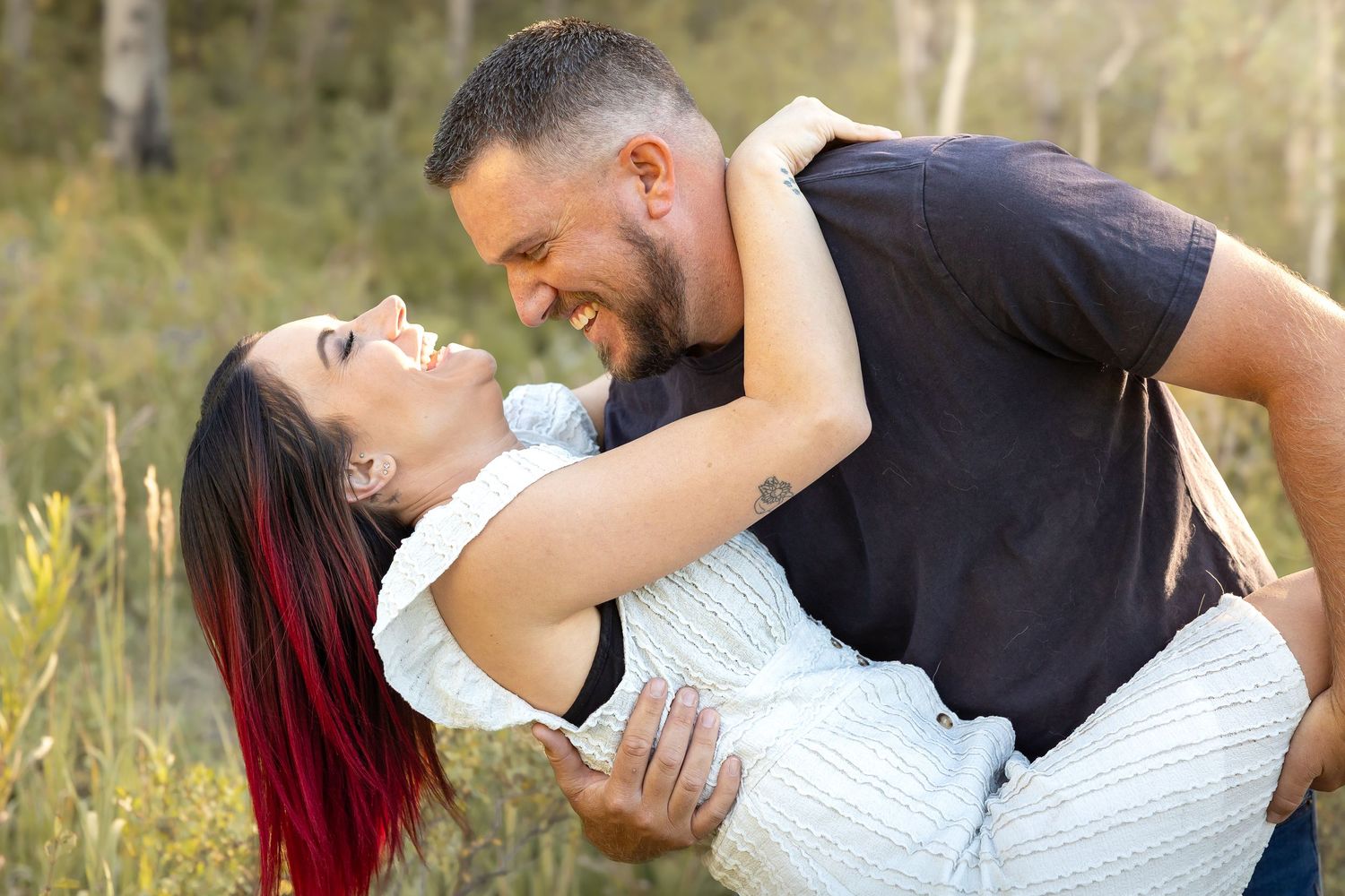 Romantic couple sharing playful dip pose in outdoor setting.