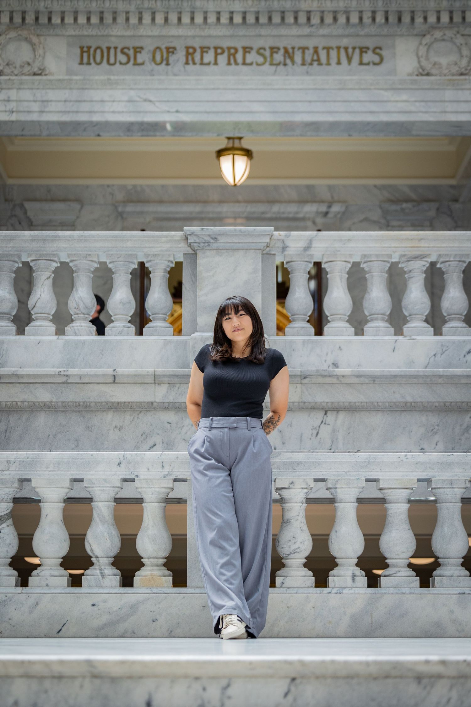 Person stands on marble steps at House of Representatives with ornate balustrade.