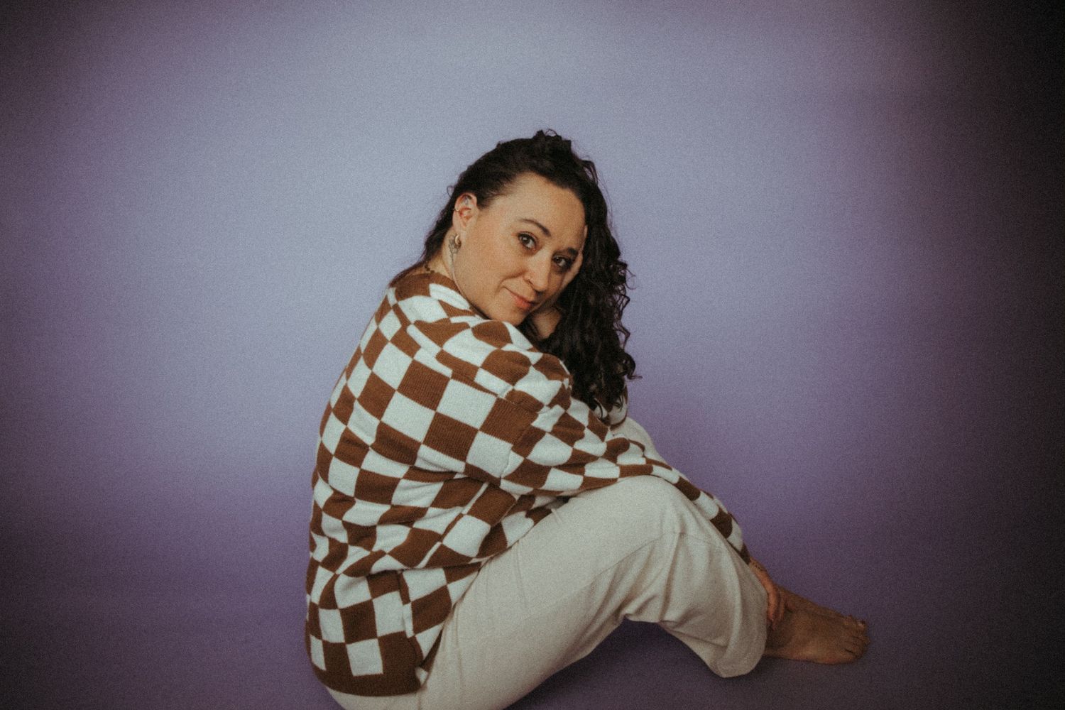 A brown and white checkered sweater is modeled in various poses against a dark background.