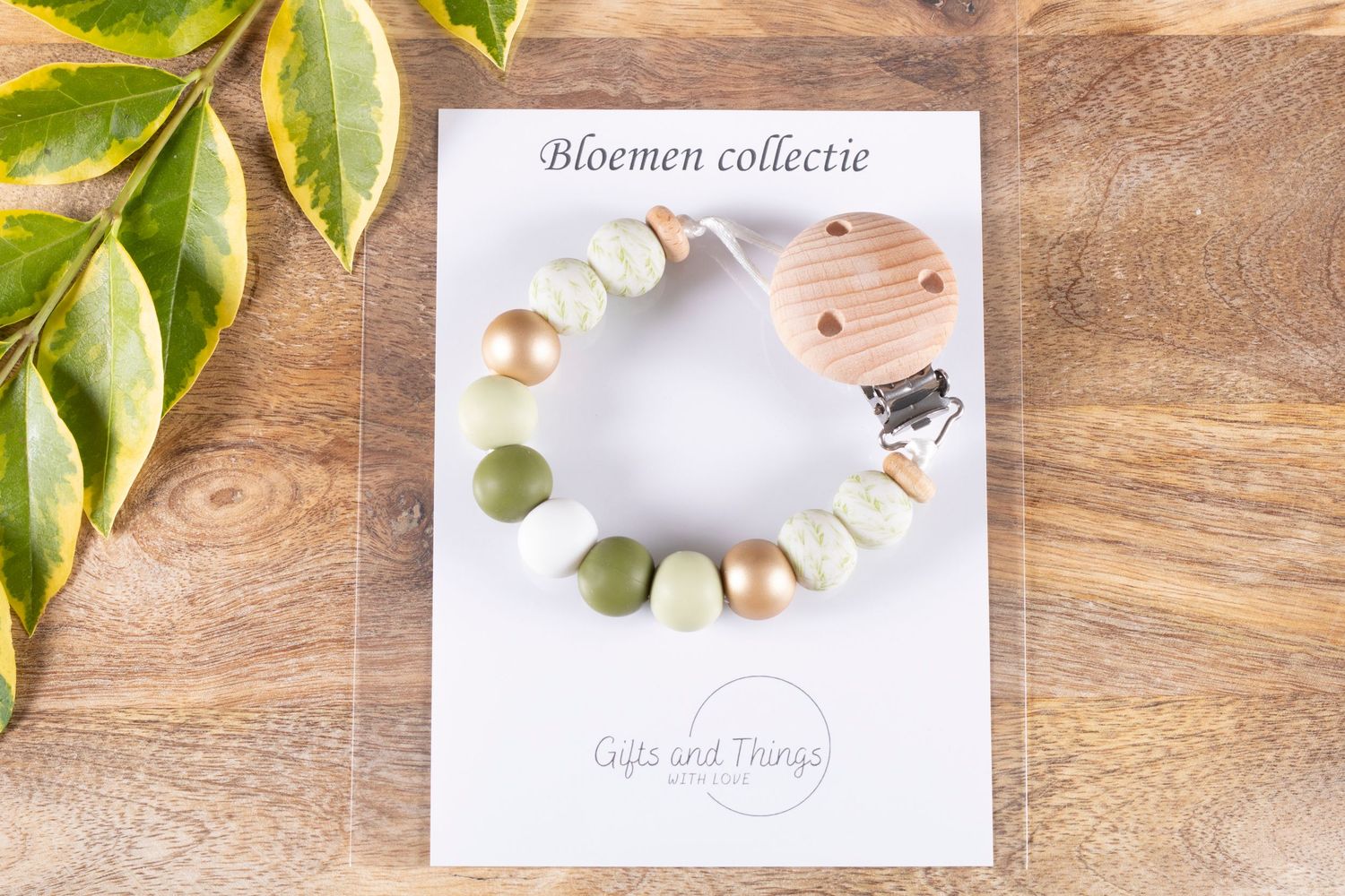 Wooden beaded jewelry displayed with green leaves on a rustic wood surface.