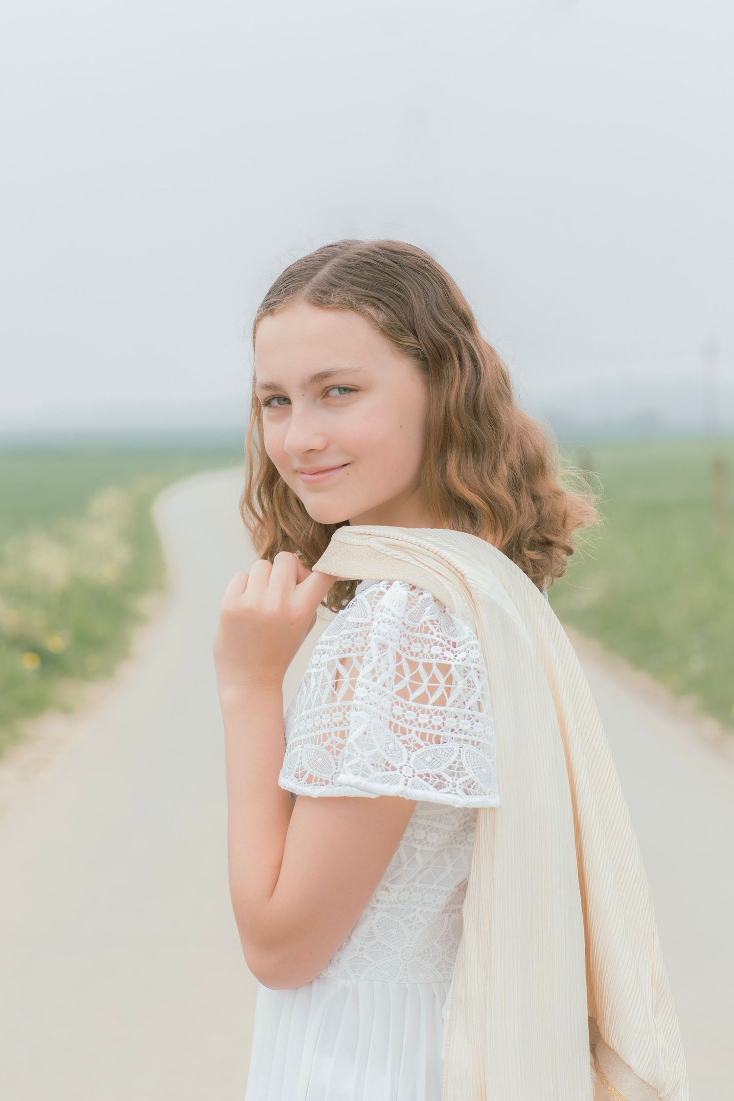 Dreamy portrait in white lace dress against soft misty background.